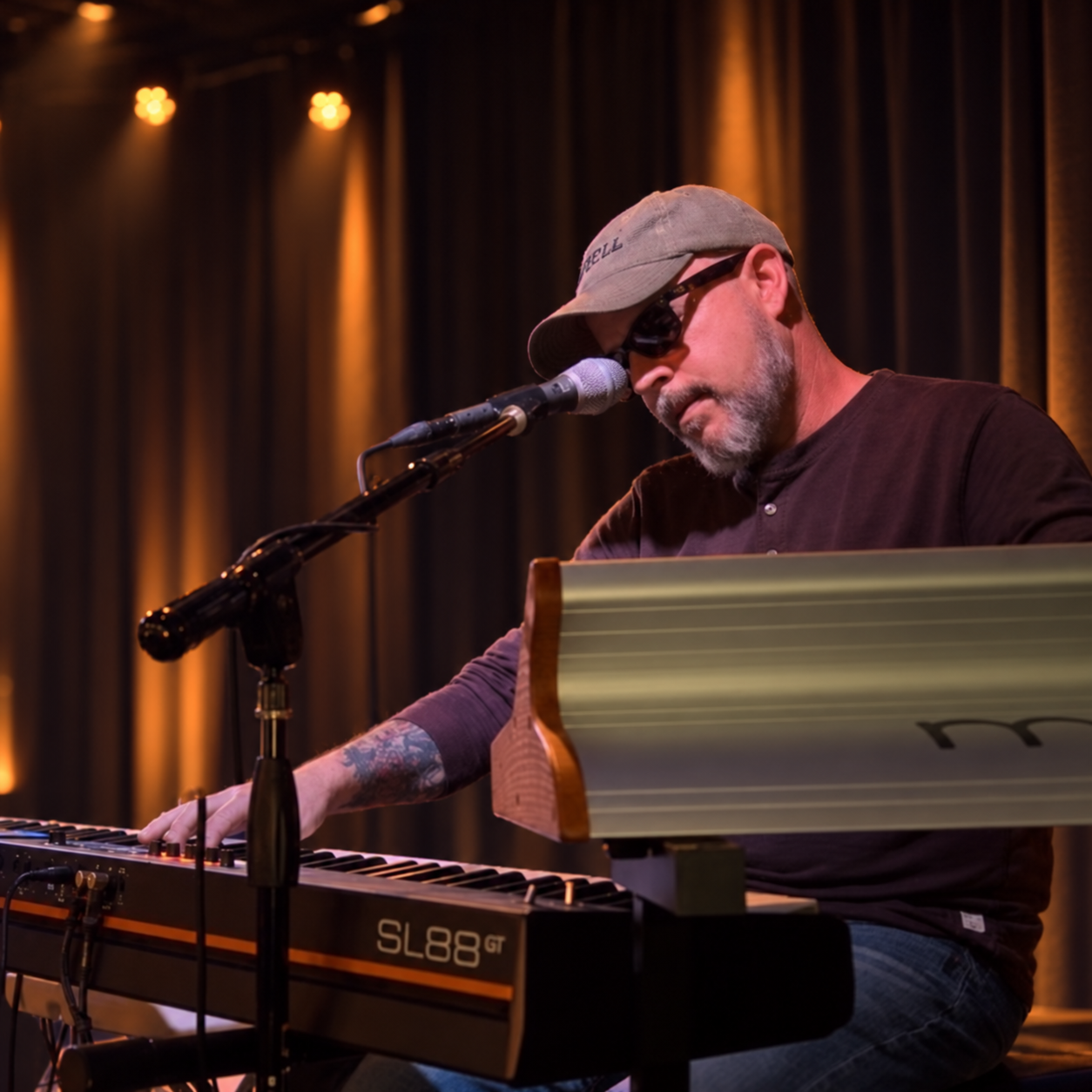 Tyler Bennett performing vocals and keyboards on a warmly lit stage